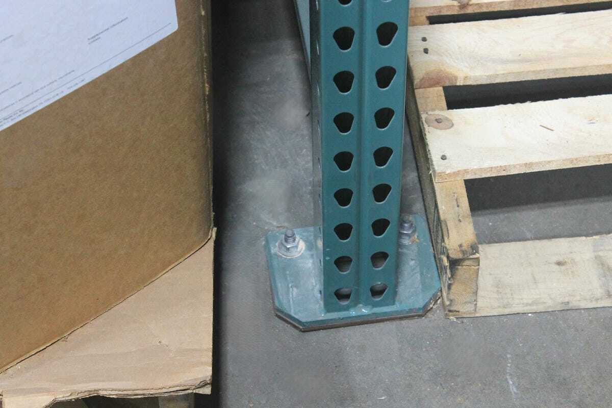 Closeup of 5x7 pallet rack footplate with two anchors into concrete